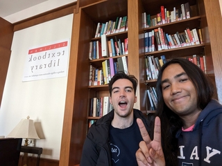 two people posing in front of a book shelf